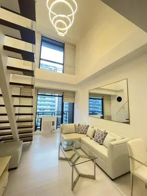 a living room with a couch and a table at Minimalist 1 Bedroom Loft Makati in Gramercy Residences in Manila