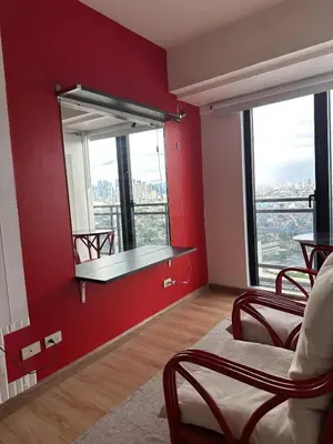 a room with a red wall with a shelf and windows at Stylish City View Flat Cozy with Netflix WIFI in The Knightsbridge Residences in Manila