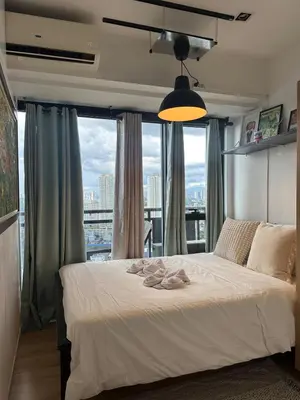 a bedroom with a white bed with a large window at Stylish City View Flat Cozy with Netflix WIFI in The Knightsbridge Residences in Manila