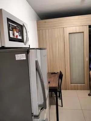 a kitchen with a refrigerator and a table with a tv on top at Ellein's Condotel in Manila