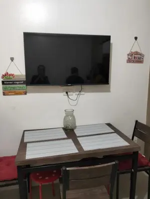 a dining room table with a television on a wall at Ellein's Condotel in Manila