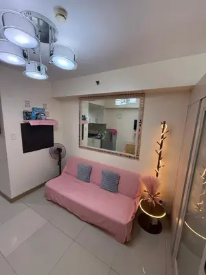 a living room with a pink couch and a mirror at R&K Staycation in Manila