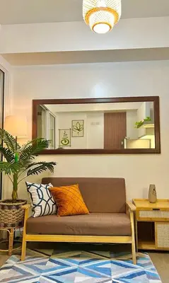 a living room with a couch and a mirror at Hiraya Pod Staycation Netflix Balcony Beach Escape in Manila