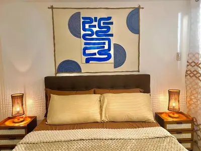 a bedroom with a bed with two lamps on tables at Hiraya Pod Staycation Netflix Balcony Beach Escape in Manila