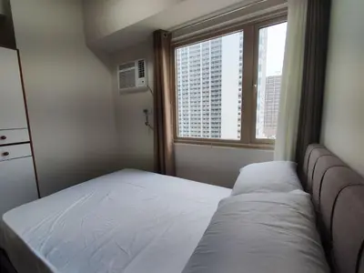 a small bedroom with a bed and a window at Manila Bay Coast Residences 1BR Flat in Manila