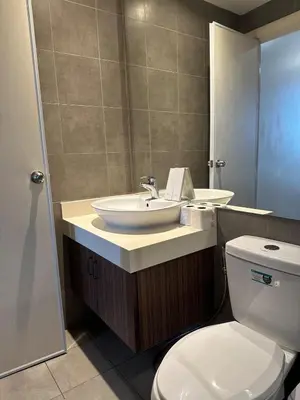 a bathroom with a white toilet and a sink at Sunset View 1 BR with balcony FREE Pool&Gym Access in Manila