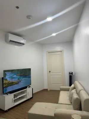 a living room with a couch and a flat screen tv at Minimalist 1 Bedroom Sunset View in Gramercy in Manila
