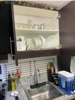 a kitchen counter with a sink and a shelf with dishes at Aiko's Haven at Kasara in Manila