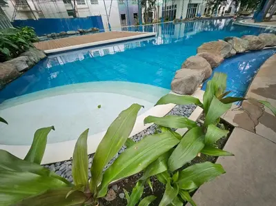 a large swimming pool with blue water and plants at Aiko's Haven at Kasara in Manila