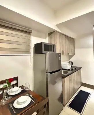 a small kitchen with a table and a refrigerator at Stylish City Escape in Manila