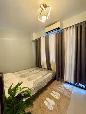 a bedroom with a bed and a window with curtains at Chic City Escape by the Bay in Manila