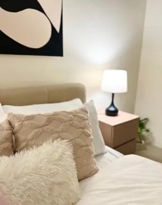 a bedroom with a bed with a pillow and a lamp at Akkomo Staycation in Manila