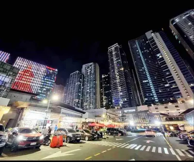 a city at night with cars parked in front of tall buildings at Uptown Parksuites Upscale Spacious Cor Unit Balcony and Views in Manila
