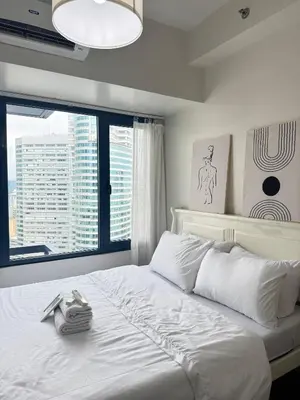 a bedroom with a white bed with a large window at Entire Place in Central Makati in Manila