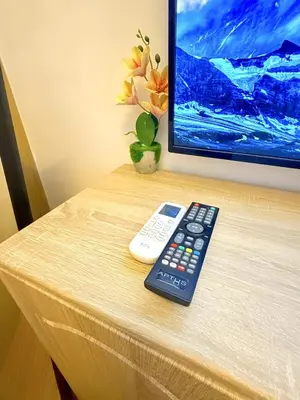 a remote control and a tv on a table at Instaworthy Space near BGC NAIA at Grace Res in Manila