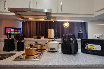 a kitchen counter with a stove and a microwave at BGC Family Suite Steps Away from Mall with FREE Parking with Washer Dryer in Manila