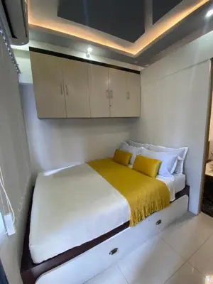 a small bedroom with a bed with yellow blanket at MGS Suite Shore 2 Residences in Manila