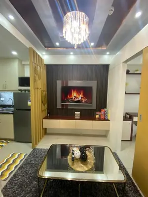 a living room with a fireplace and a chandelier at MGS Suite Shore 2 Residences in Manila