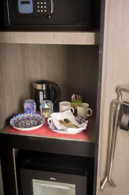 a table with plates and cups on top of a cabinet at Stay Across NAIA Terminal 3 in Newport City in Manila