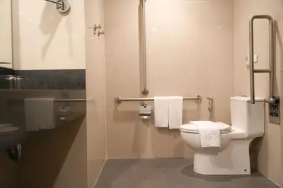 a bathroom with a toilet and a shower with towels at Stay Across NAIA Terminal 3 in Newport City in Manila