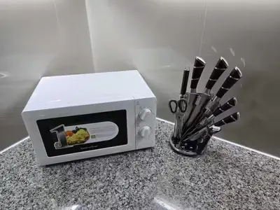 a microwave on a counter next to a container of knives at Modern Comfort & Snap Worthy with Pool, Gym & More in Manila