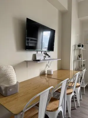 a dining room with a table with chairs and a flat screen tv at Jac's Hide Out 5 in Manila