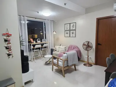 a living room with a chair and a desk at Cozy 1BR Corner with Panoramic City Skyline View in Manila