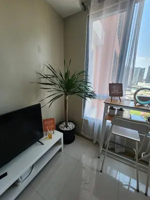 a living room with a tv and a potted plant at Cozy 1BR Corner with Panoramic City Skyline View in Manila