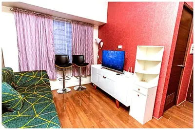a living room with a tv and two chairs in a room at 2 bedroom fantastic air condo 3649 swim gym surf 300 MB in Manila
