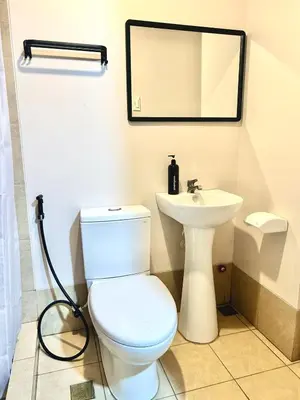 a bathroom with a white toilet and a sink at Cozy Studio near Nuvali, Enchanted Kingdom - Private Cinema with Netflix & Disney Plus with Free Pool Access in Silang