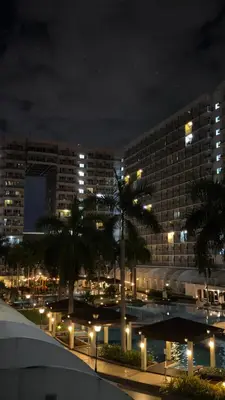a large building with palm trees in front of it at night at Spacious Condo at Shell Residences, MOA Pasay - The Urban Stay in Manila