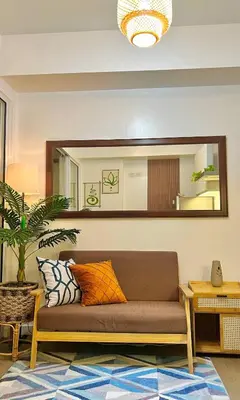 a living room with a couch and a mirror at 15 Mins Away from NAIA Perfect for Staycation in Manila