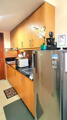 a kitchen with a stainless steel refrigerator and wooden cabinets at Urban Retreat at Shell Residences with Netflix 300mbps Wifi in Manila