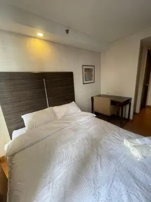 a bedroom with a large white bed and a desk at A Venue Residences 9133 in Manila
