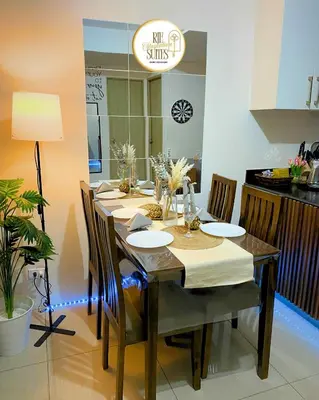 a dining room with a table with chairs and a kitchen at RJE Staycation Suites Mall of Asia near Airports in Manila