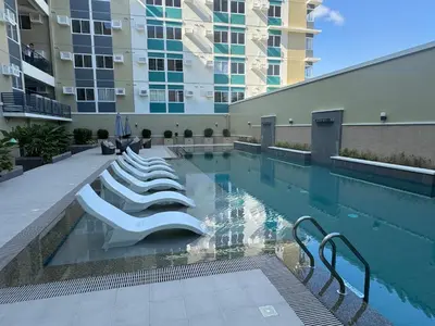 a swimming pool with lounge chairs in a building at Berkeley Suites, Silang Cavite in Silang
