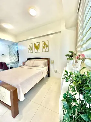 a bedroom with a bed and plants in it at Chic Unit with Balcony - Free wifi & netflix across Naia Terminal 3 Airport in Manila