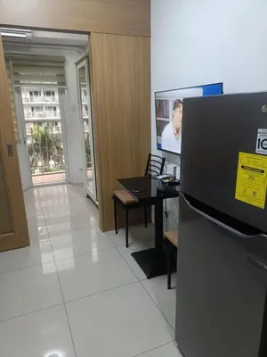 an office with a tv and a table and a refrigerator at Shell Residences in Manila