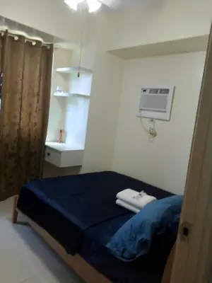 a bedroom with a bed and a air conditioner on the wall at MOA Staycation - by Marites in Manila