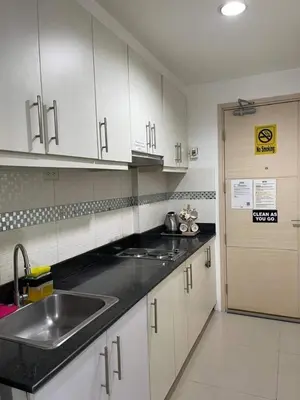 a kitchen with white cabinets and a sink and a door at Joyce Condo unit Sea Residences in Manila