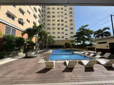 a swimming pool with lounge chairs in front of a building at Casa Chloe at Holland Park in Biñan