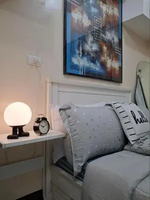 a bed with a lamp and a clock on a table at Cozy Studio Unit McKinley Hill in Manila