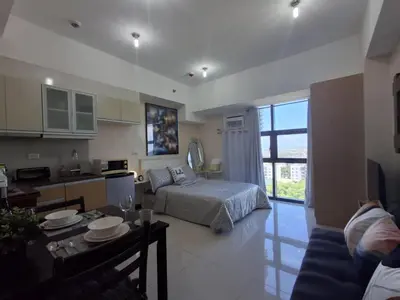 a bedroom and a living room with a bed and a table at Cozy Studio Unit McKinley Hill in Manila