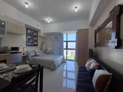 a living room with a bed and a dining table at Cozy Studio Unit McKinley Hill in Manila