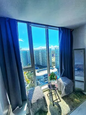 a room with a large window with blue curtains at St Tropez PH 07 in Manila