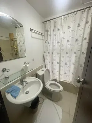 a bathroom with a sink and a toilet and a shower curtain at A venue Residences 1801 in Manila