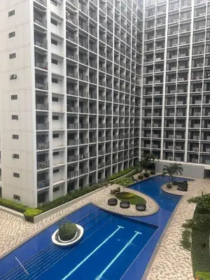 a large building with a swimming pool in front of a building at 1 Bedroom Condo at Shore 2 Near Airport with Balcony & Pool View in Manila