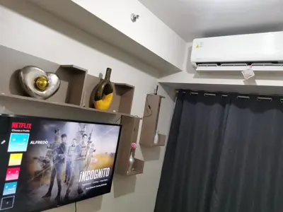 a living room with a tv and a curtain at Mall of Asia Shore condo in Manila