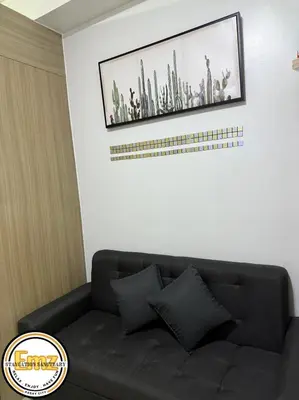 a black couch in a room with a picture on the wall at EMZ SHORE2 Staycation 16 in Manila