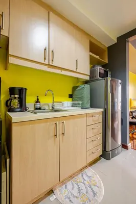 a kitchen with wooden cabinets and a stainless steel refrigerator at Central Stay w King bed near Greenbelt 55-In TV in Manila